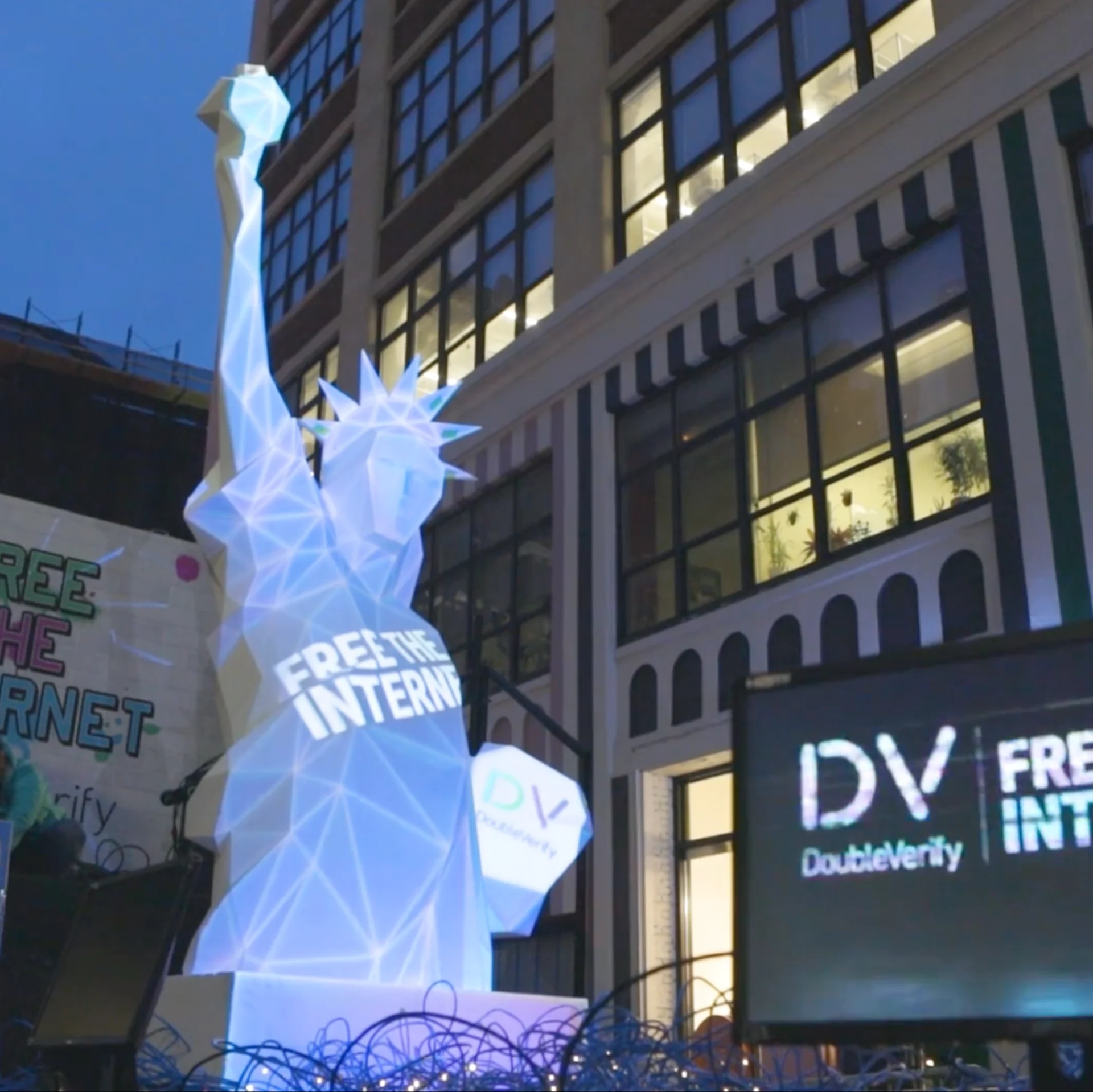 DoubleVerify, « Free the Internet » : la statue de la Liberté taillée en facettes, éclairée de bleu, le message « Free the Internet » projeté sur sa robe et le logo DV sur sa tablette, devant un immeuble de New York