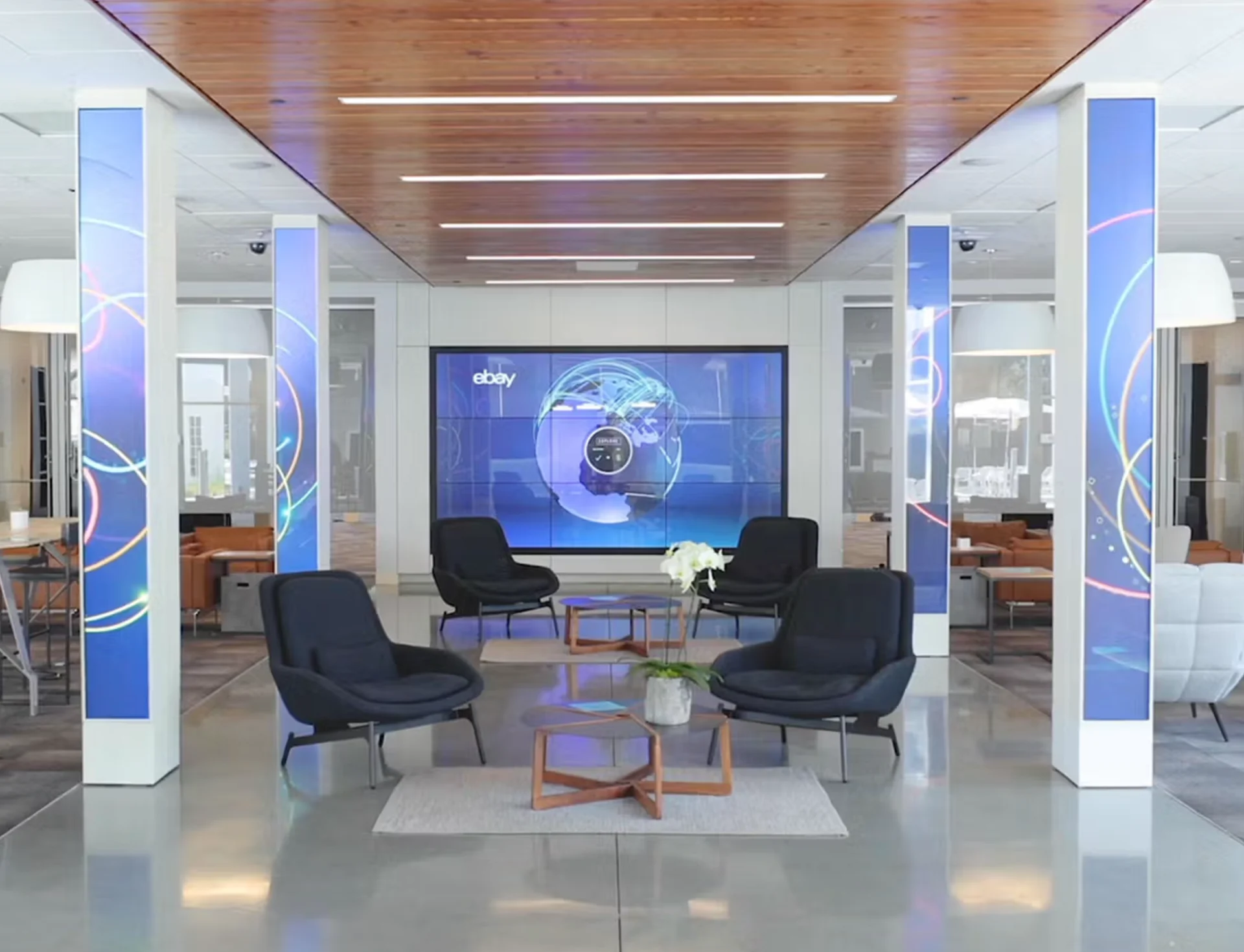 eBay Earth : le mur vidéo au globe dans le hall du campus d'eBay, entre des colonnes lumineuses et des fauteuils