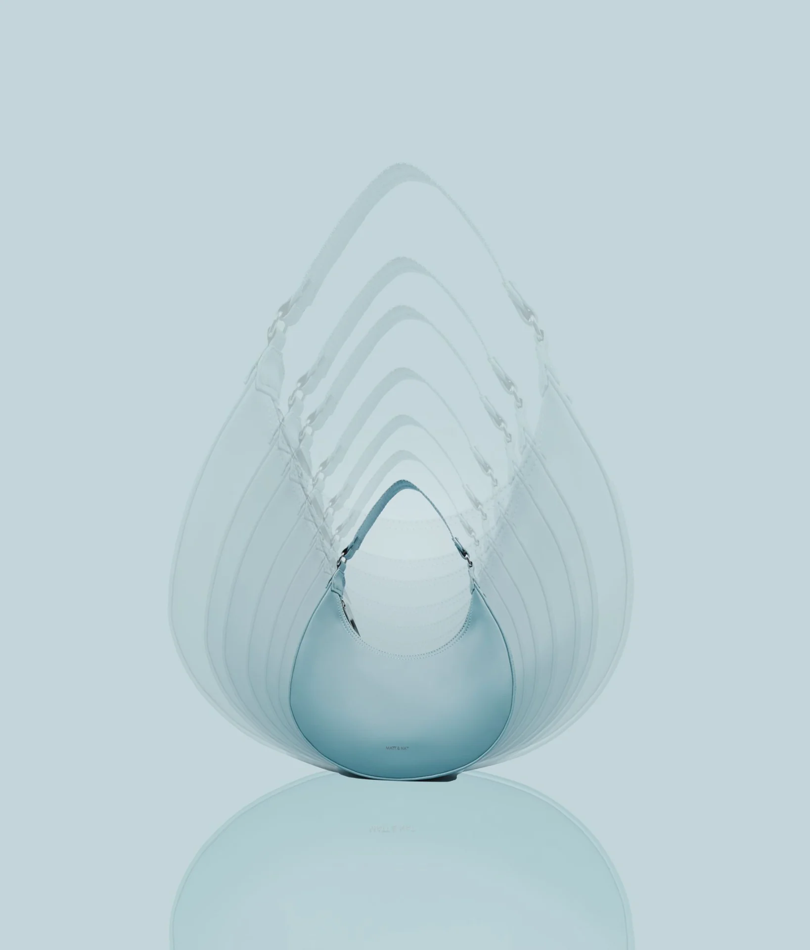Matt & Nat : un sac bleu glacier et la trace de son mouvement, en éventail, sur fond bleu pâle