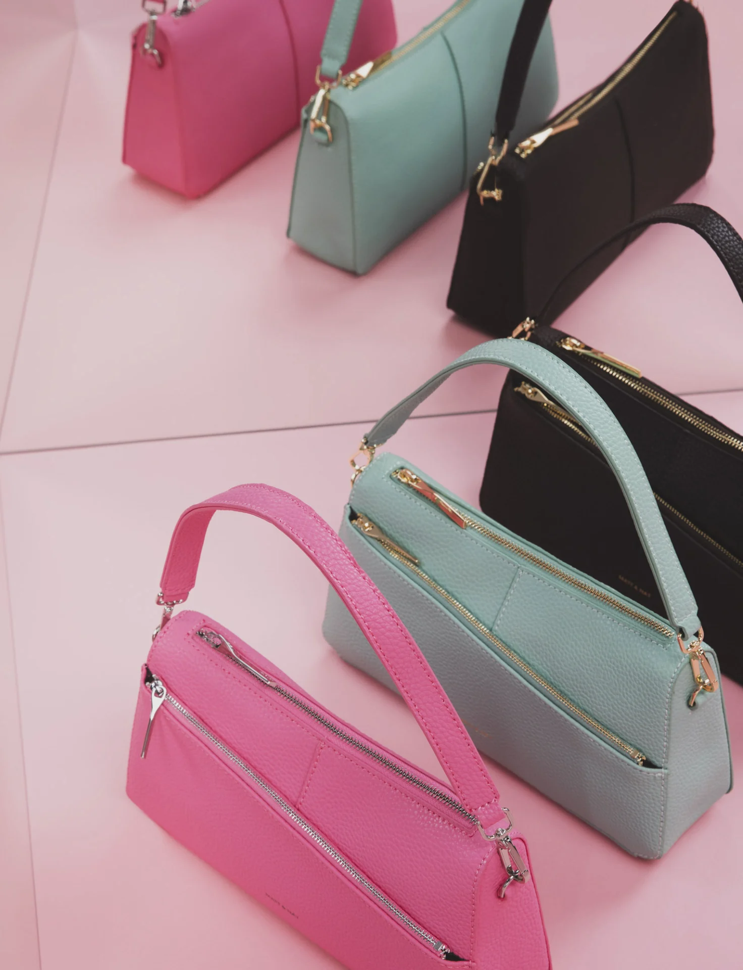 Matt & Nat : sacs rose, menthe et noir alignés sur un sol rose