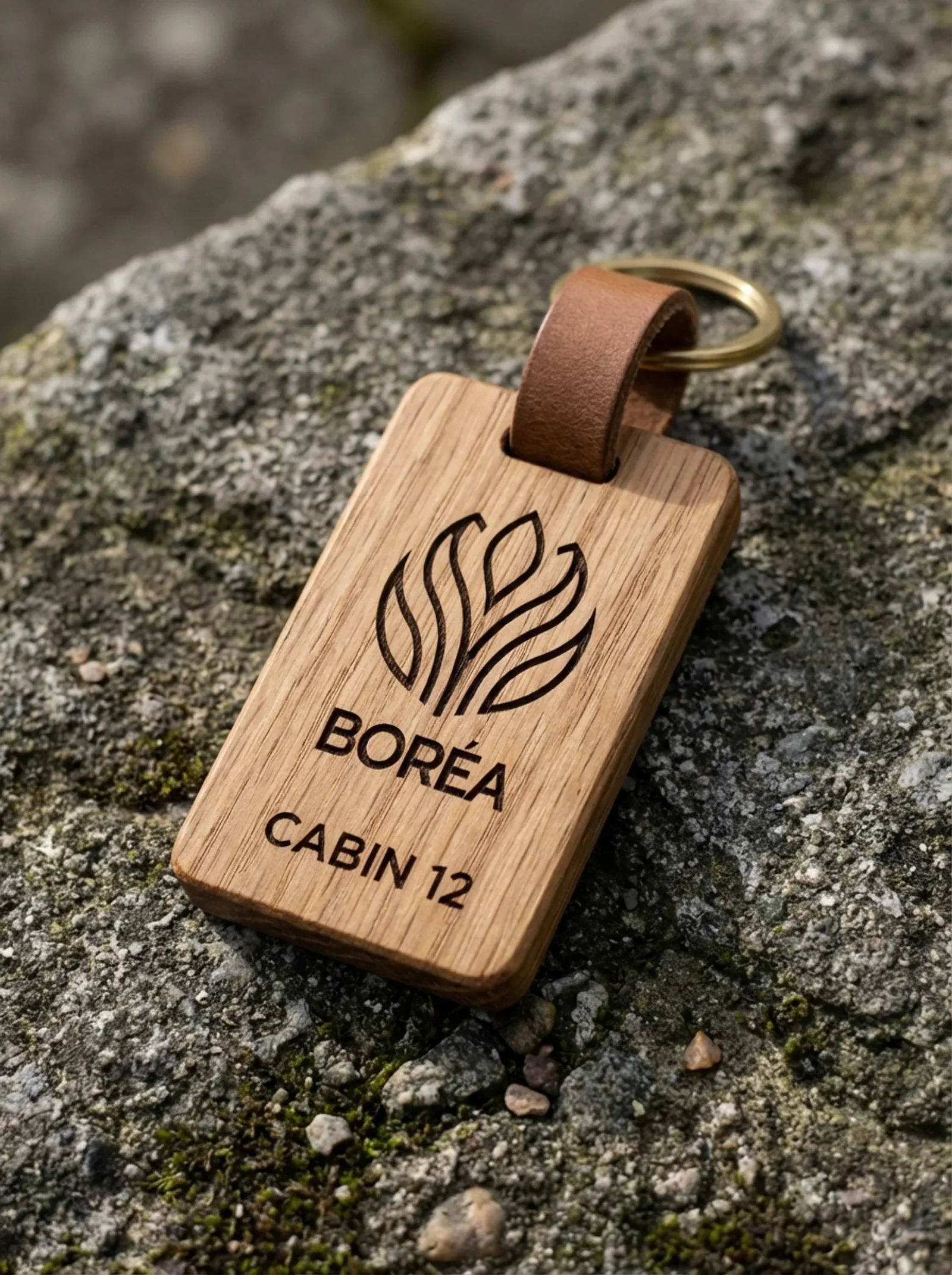 Boréa : la clé de cabine en chêne, le signe et « Cabin 12 » gravés, posée sur une pierre moussue