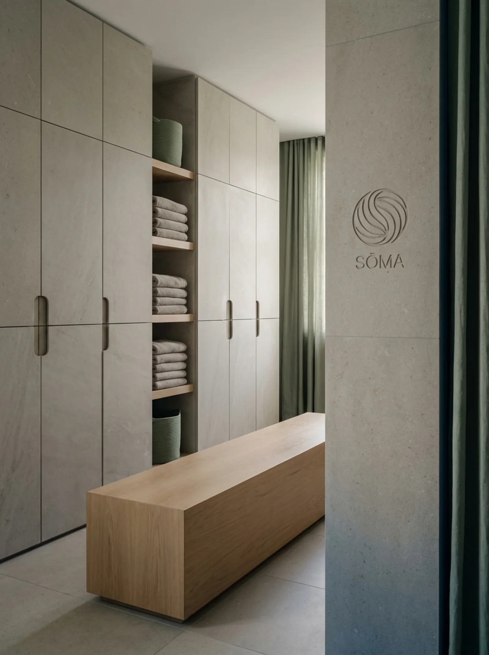 Sōma : le vestiaire en pierre grise, le signe et le nom gravés sur un pilier, un banc de chêne