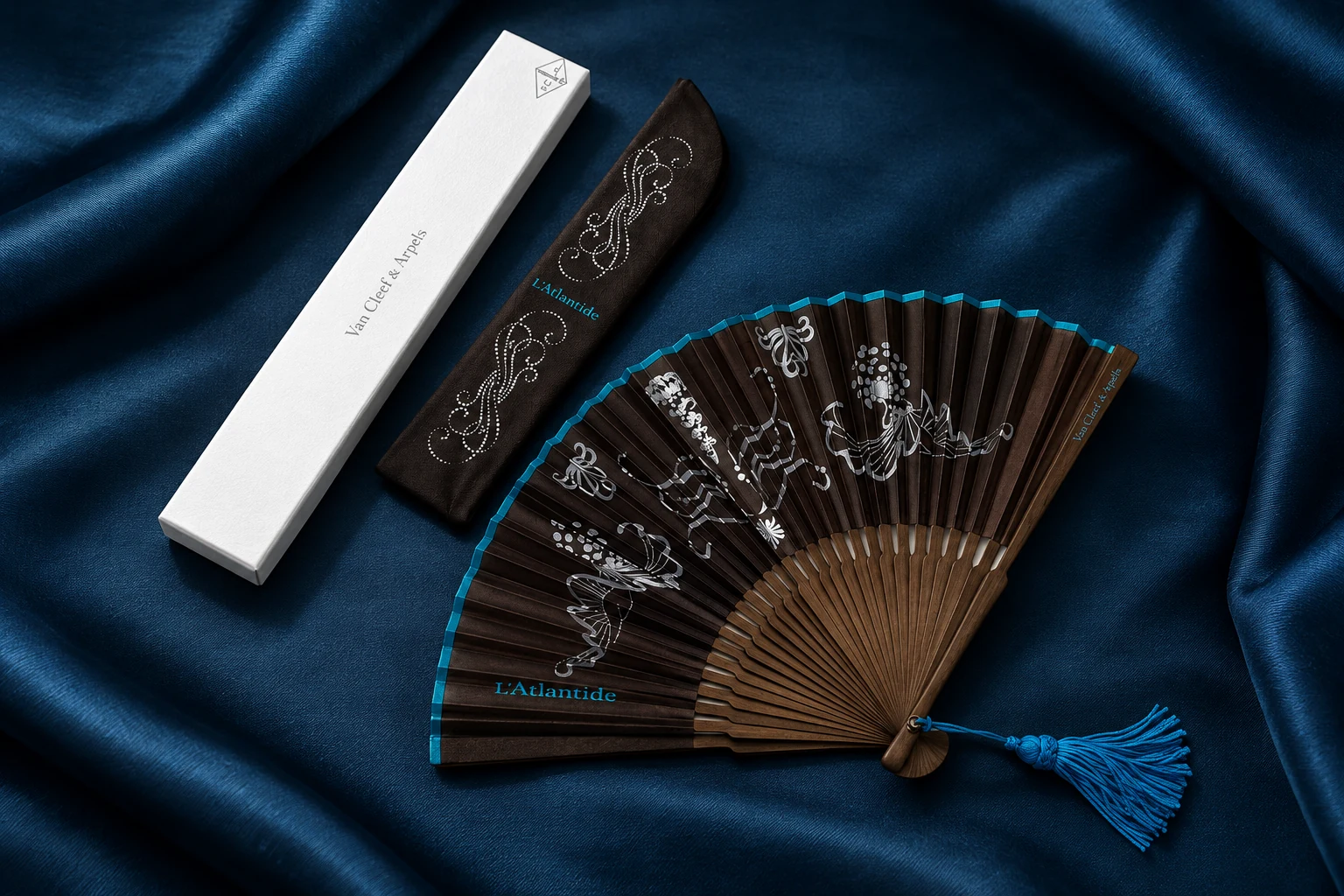 Van Cleef & Arpels, collection L'Atlantide : l'éventail brun à motifs marins argentés, son étui et sa boîte, sur un satin bleu nuit
